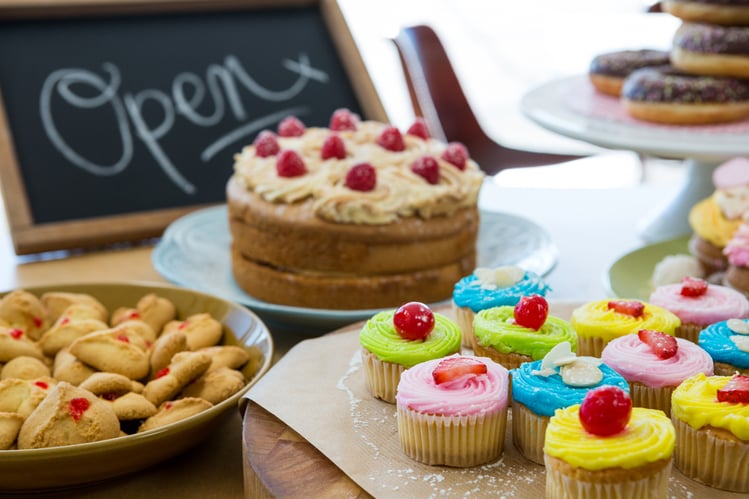 Close-up of various sweet foods on table with open signboard in cafeteria